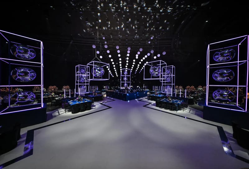 Large dark Hangar hall with neon-edged cubes of mirrored spheres, LED walls on both sides and a lit white dance floor