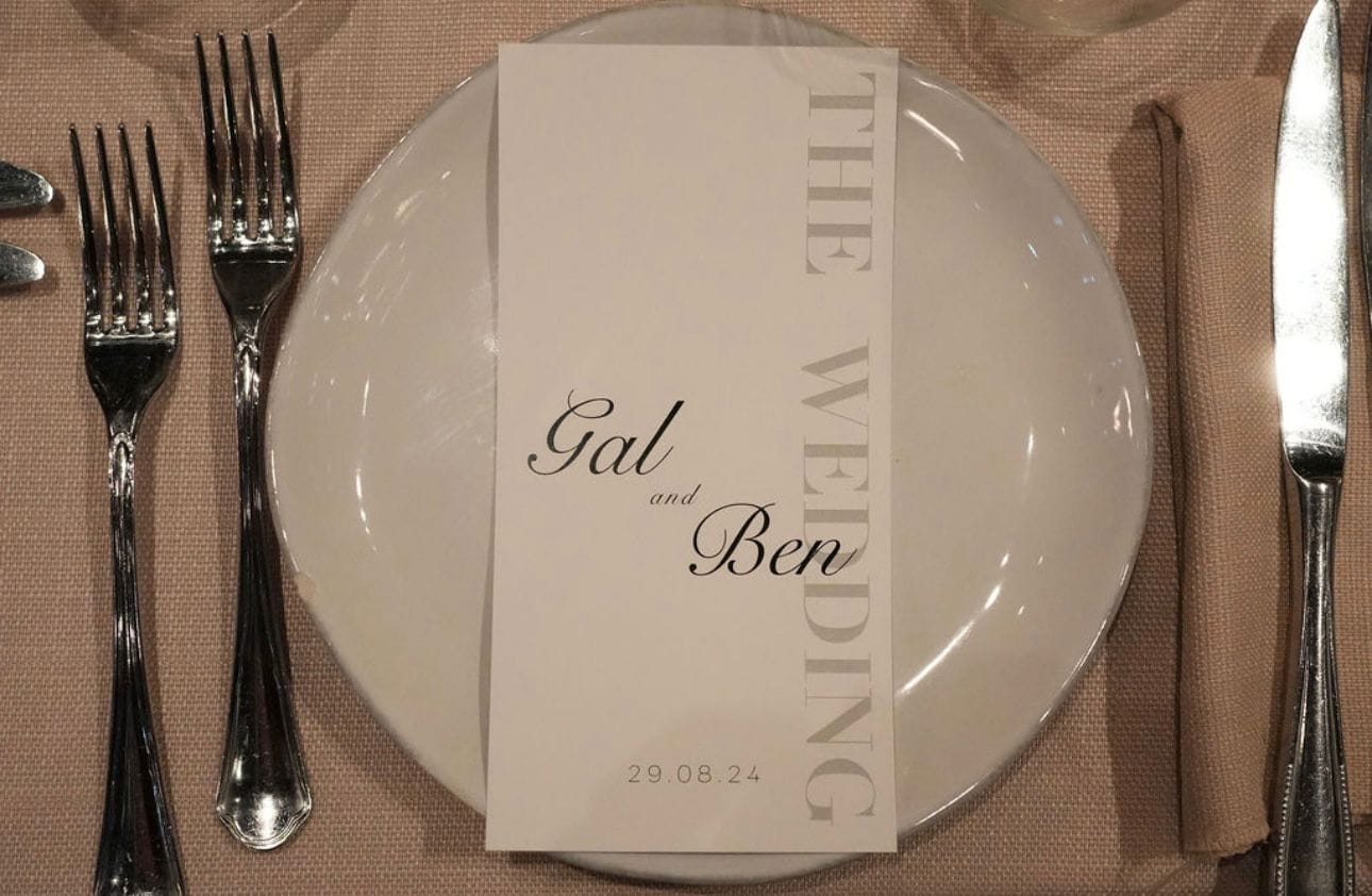 Couvert dressé avec assiette blanche, carte de menu imprimée, fourchettes, couteau et serviette