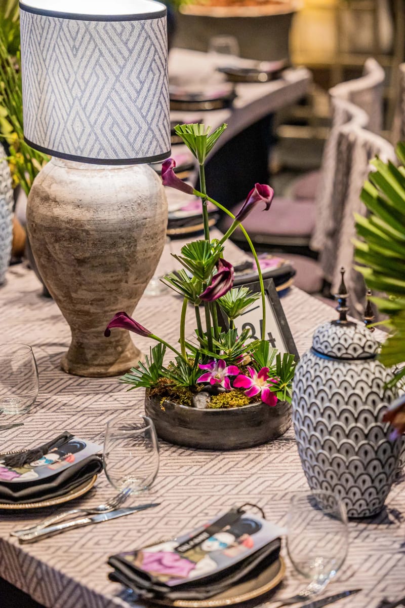 Table set with a geometric-pattern cloth, ornate ceramic vases, graphic-print napkins and a calla plant in a bowl
