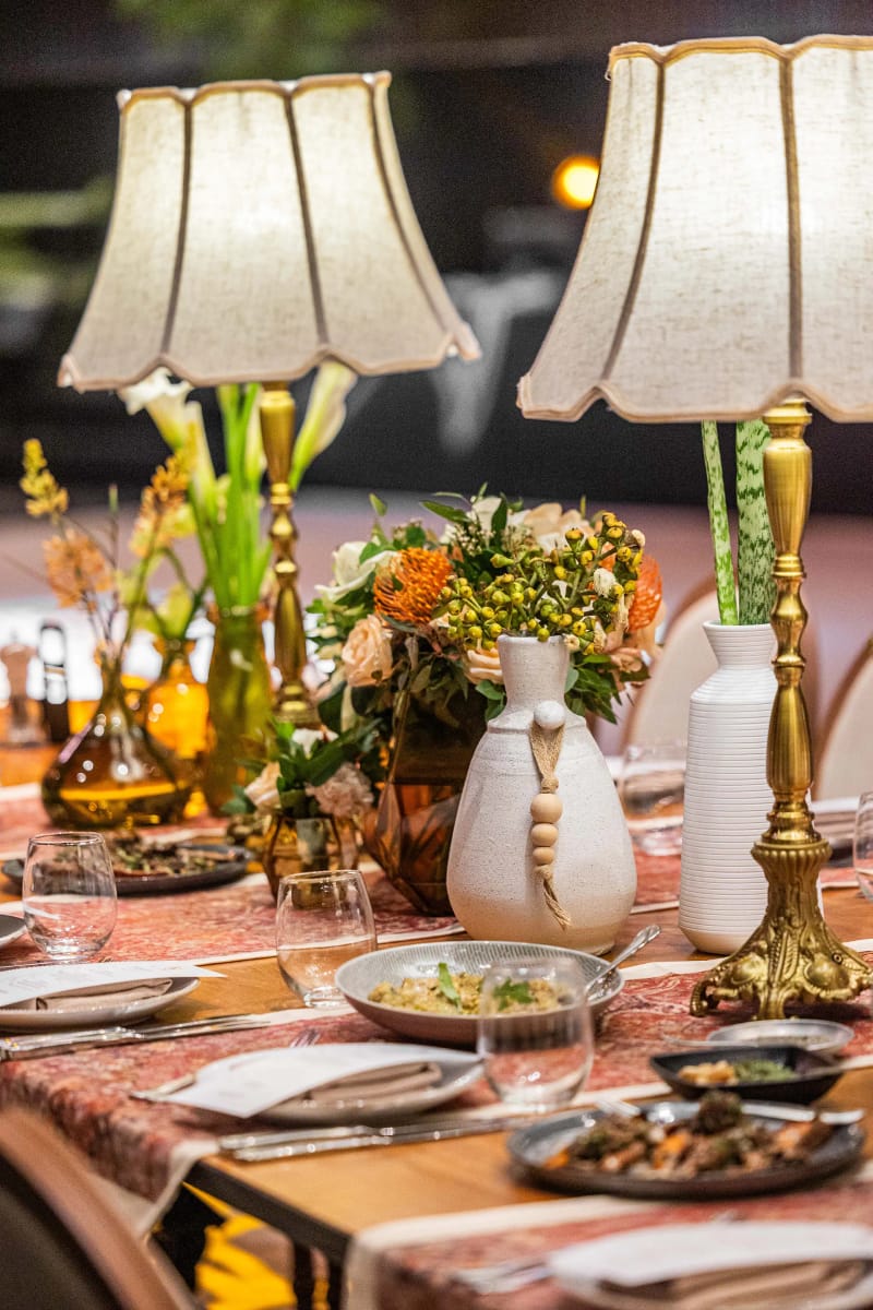 Deux lampes à abat-jour et hautes fleurs dans des vases blancs avec une feuille verte, sur une table au chemin à motifs