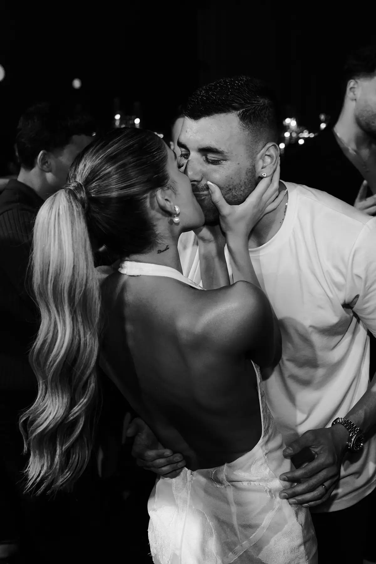 Image en noir et blanc d'un couple s'embrassant, la femme en robe dos nu avec une longue queue de cheval, l'homme en t-shirt blanc