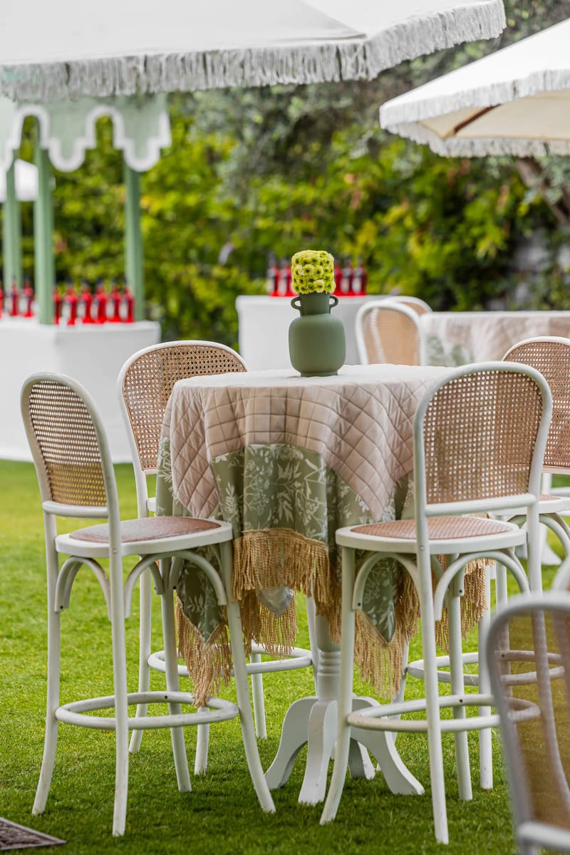 Table haute à nappe à franges et tabourets de bar blancs au dossier cannelé sur la pelouse